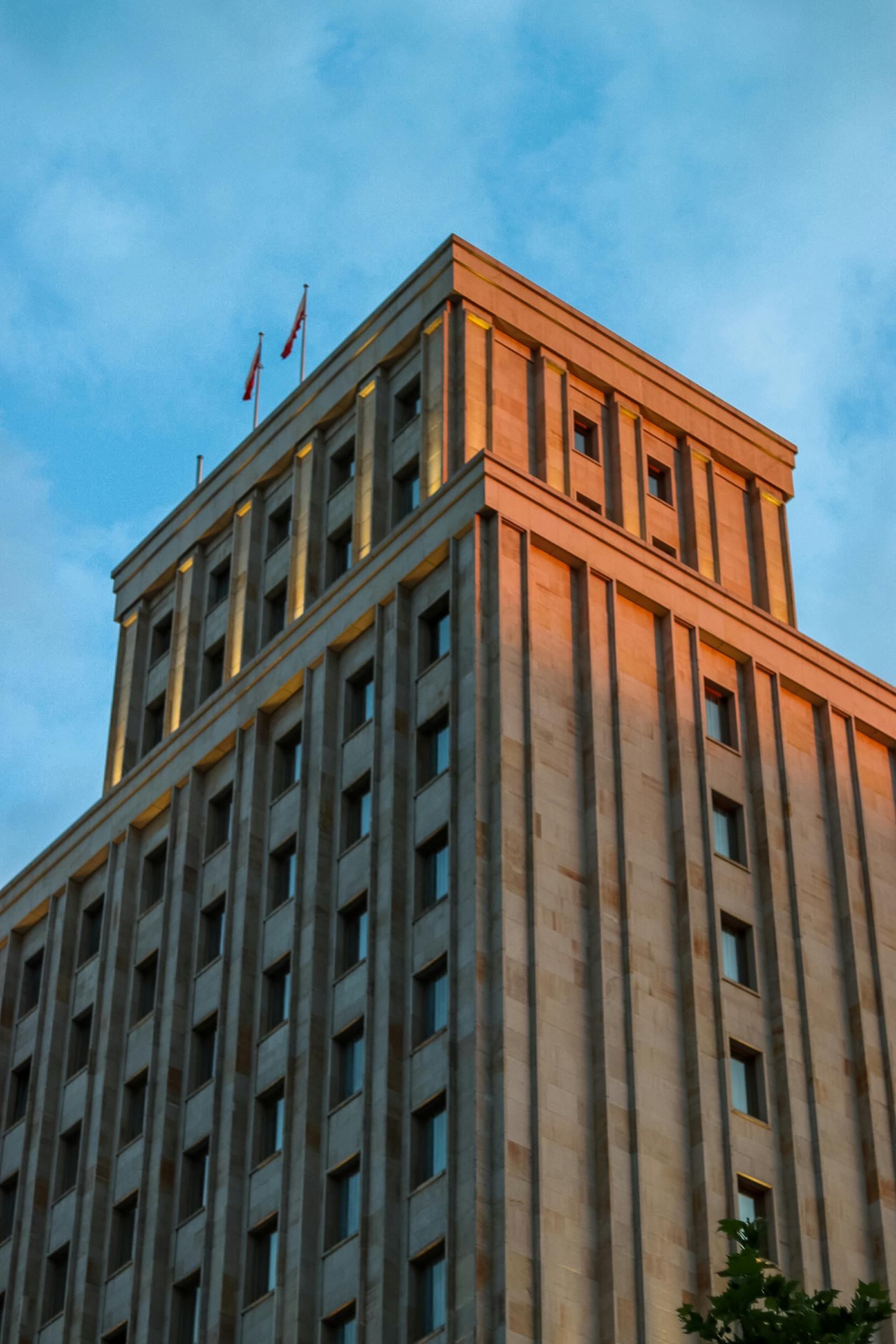 A contemporary multi-story building with flags at sunset, showcasing modern architecture.
